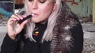 Blonde lady smokes an electronic cigarette on stair