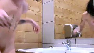 Inked vixen poses naked and masturbates in a public toilet