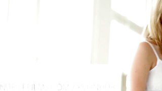 Two blondes share standing blowjob while one lounges on white sofa